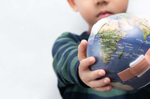 Closeup banner of a cute little asian boy a new generation presenting a damage globe full of bandages. Global warming, Climate change, Environmental problems. World pollution, Earth day, Net zero.